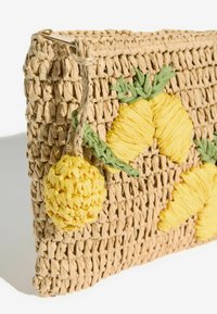 Pochette beige tissée avec des applications ananas jaunes et des détails de feuilles vertes, dotée d'un charm ananas crocheté sur la fermeture éclair.