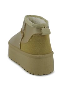 Lichtbeige enkelboot met een zachte textuur, een dikke platformzool en een trekband aan de achterkant. Heeft een mix van gladde en suède afwerkingen.