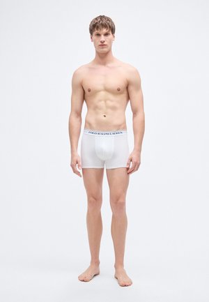 Boxer in cotone bianco con fascia elastica in vita con il logo "POLO RALPH LAUREN" in blu navy. Il modello è in piedi a piedi nudi, di fronte.