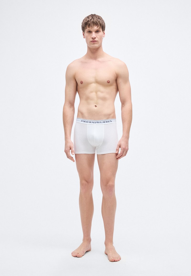 Valged puuvillased bokserpüksid, millel on elastne vöökoht ning tumesinisel taustal "POLO RALPH LAUREN" logo. Mudel seisab paljajalu, otsa vaadates.