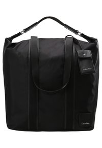 Zwarte nylon tote bag met dubbele handvatten, een strak ontwerp en een logo-tag. Accentuaten met subtiele verticale stiksels en een afneembare leren tag.