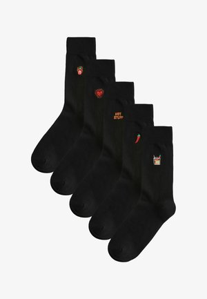 Pět černých ponožek, každé s malou barevnou výšivkou: hořící srdce, červené srdce, nápis „HOT STUFF“, chilli paprička a pikantní nápoj.