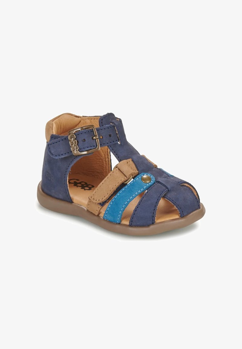 Sandale pour enfants en cuir bleu marine et tan avec boucle ajustable et bride accent bleue, bout ouvert et semelle en caoutchouc.