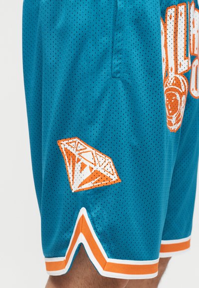 Kék kosárlabdazokni narancssárga és fehér szegéllyel, amelyen a szegély közelében egy nagy narancssárga és fehér gyémántmotívum található.