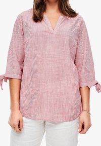 Blouse rayée rouge et blanche avec un col en V et des manches trois-quarts, dotée de détails noués et d'une coupe décontractée. Texture de tissu douce.