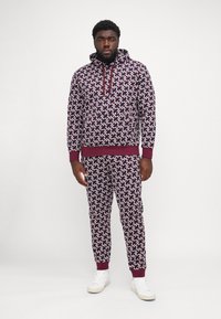 Hætte sweatshirt og matchende bukser i et mønster af maroon, hvid og navy. Har ribbede manchetter og kant, afslappet pasform og lommer.