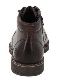 Stivali ankle in pelle marrone con punta arrotondata, chiusura con zip e cuciture a contrasto. Suola in gomma piatta con finitura testurizzata.