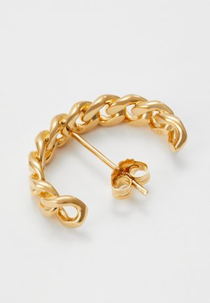 Boucle d'oreille demi-anneau à gros maillons en métal doré avec tige et fermoir papillon, posée sur une surface blanche.