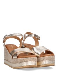 Sandalias cuña doradas metálicas con dobles tiras cruzadas, plataforma envuelta en tela y una plantilla suave similar al cuero.