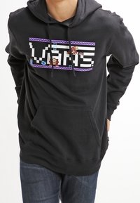 Sweat à capuche noir avec un design graphique comprenant le texte "VANS" et des éléments de jeu vidéo. Comprend une poche frontale et une capuche avec cordon de serrage ajustable.