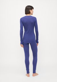 Violet spalvos ilga rankovėmis viršus ir derančios legging kelnes, prigludusi dizaino, minkšta tekstūra, be siūlių apdaila, su ilgomis rankovėmis ir iki kulkšnies ilgio rankogaliais.
