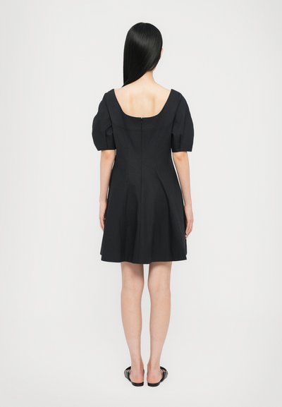 Black dress with short puff sleeves, low back, and a flared skirt. Made from a smooth fabric with a concealed zipper at the back.