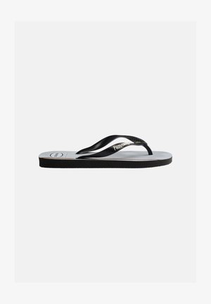 Sort-hvid klipklap sandal med sorte teksturerede remme og "havaianas"-logo på en lysegrå sål mod en ensfarvet baggrund.