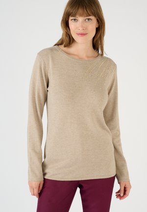 Suéter beige de manga larga con escote redondo y adornos dispersos en tonos dorado y plateado, hecho de una tela suave y texturada.