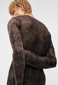 Suéter de malha canelada de manga comprida em castanho escuro com riscas mais claras. Apresenta uma silhueta ajustada e uma textura suave. Detalhe franzido ao longo das costuras.