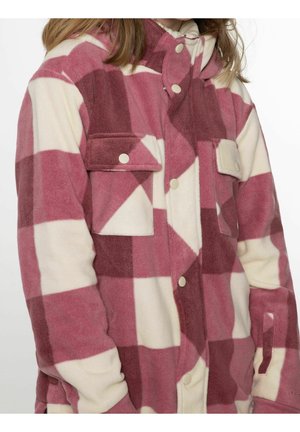 Person iført en fleecejakke med stort ternet mønster i pink og creme samt lommer med trykknapper på brystet og forsiden.