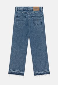 Wide-leg blue denim jeans with a frayed hem, two back pockets, and a leather label at the waistband. Soft texture and light wash finish.