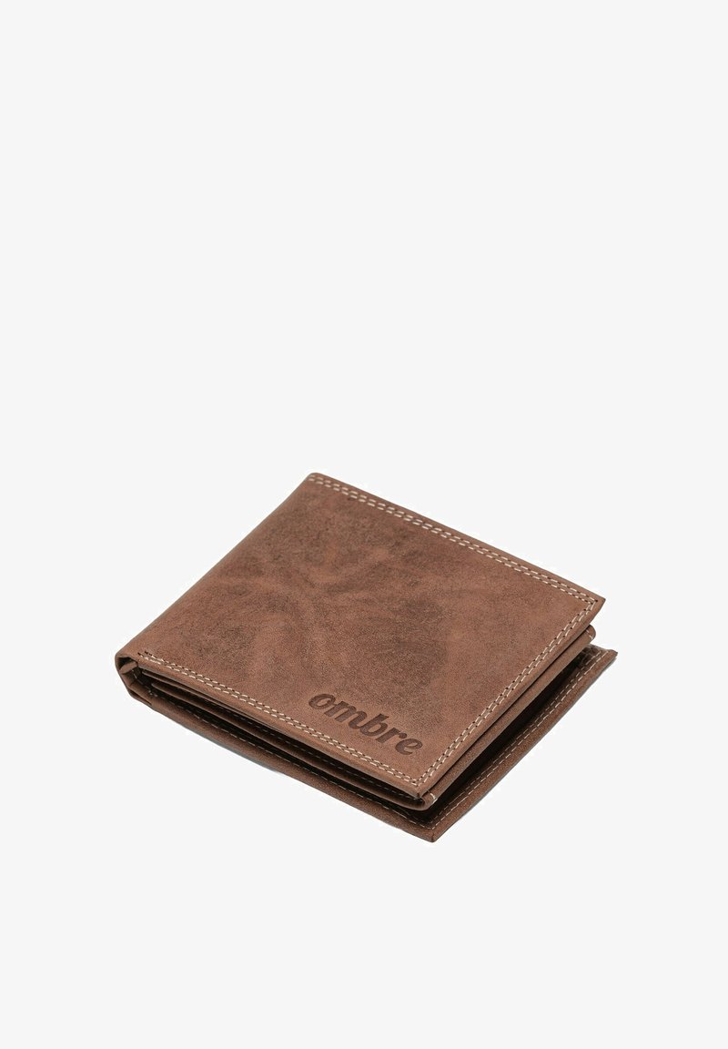 Portefeuille en cuir marron avec des coutures visibles et un logo "ombre" en relief. Design plié, texture lisse, forme compacte.