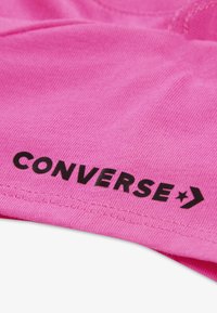 T-shirt rosa in cotone con logo "CONVERSE" nero e grafica a stella. Tessuto morbido, design a maniche corte, con scollo rotondo.