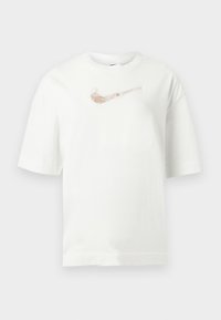 Λευκό κοντομάνικο T-shirt με μεταλλικό λογότυπο Nike σε ροζ χρυσό στο κέντρο του στήθους, πάνω σε ανοιχτό γκρι φόντο.