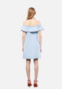 Vaaleansininen olkaimeton farkkuasu, jossa on röyhelökaula-aukko, takaosan saumat sekä suora leikkaus polven ylle.