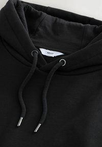 Schwarzer Hoodie mit einer Zugverlängerung, silbernen Metallakzenten an den Enden der Zugverlängerung und einem weichen, strukturierten Stoff. Das Etikett trägt die Aufschrift "NEXT."