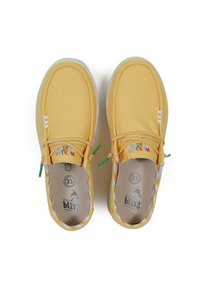 Yellow canvas shoes with white stitching, green accents, and patterned interior. Features a slip-on design and rounded toe.