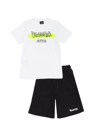 Maglietta bianca in cotone con testo grafico verde neon sul davanti, abbinata a pantaloni corti neri con testo del logo bianco sull'orlo.