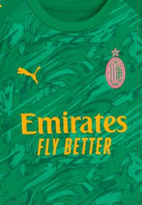 Maglia sportiva verde con texture astratta, caratterizzata da un logo Puma giallo e il testo arancione brillante "Emirates FLY BETTER" sopra il materiale.