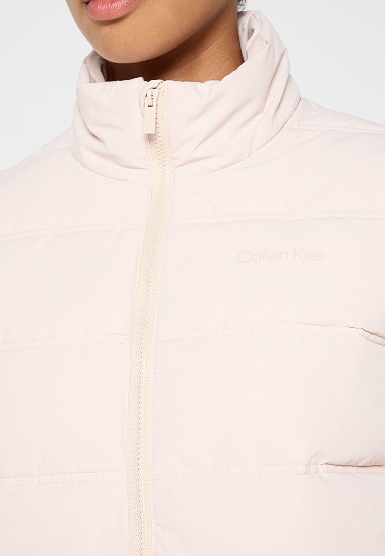 Gewatteerde roze jas met een hoge kraag, een ritssluiting aan de voorkant en een subtiele Calvin Klein-logo. Gladde textuur met horizontale stiksels.