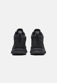 Scarpe da ginnastica nere con tomaia in mesh texturizzato, colletto imbottito e suola in gomma spessa. Presentano un tallone rinforzato e accenti riflettenti.