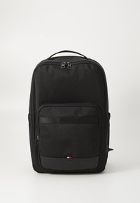 Black backpack with a textured surface, zip closure, front pocket, and a logo patch in the bottom corner featuring red, white, and blue accents.