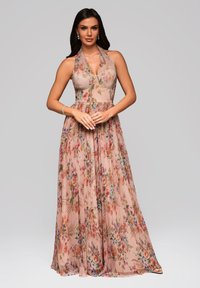 Kwiatowa suknia maxi w delikatnym różowym materiale, z halterem, dopasowaną górą i zwiewną spódnicą, która prezentuje żywy wzór kwiatowy.