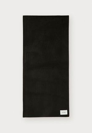 Serviette en tissu noir avec une texture lisse, de forme rectangulaire, et une petite étiquette blanche dans le coin inférieur droit. Design simple et minimaliste.