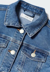 Jeansjacka i ljusbl�å färg, klassisk krage och metallknappar. Utmärkande detaljer inkluderar två framfickor och synlig sömnad.