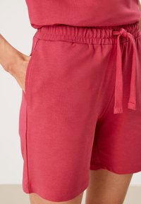 Czerwone szorty z mieszanki bawełny, wyposażone w elastyczny pas ze ściągaczem, boczne kieszenie oraz gładką fakturę.