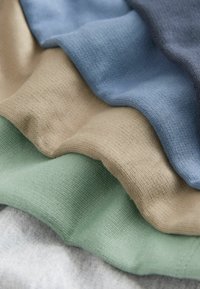 Campioni di tessuto di cotone impilati nei colori grigio, verde chiaro, beige, azzurro e blu scuro. Le trame sono morbide e a coste.