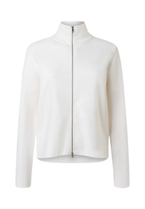 Witte gebreide jas met lange mouwen, hoge kraag en een zilveren ritssluiting over de hele lengte aan de voorkant.
