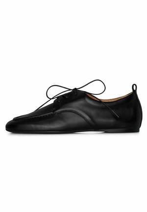 Chaussure habillée en cuir noir à lacets, avec bout pointu et petit talon, vue de profil sur fond blanc.
