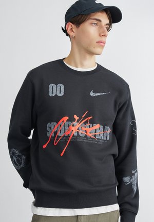 Crna dukserica s okruglim izrezom, s grafičkim printovima, uključujući "00" i crveni Nike logo. Izrađena od mekanog materijala s dugim rukavima.