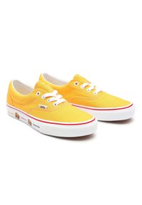 Baskets en toile jaune avec lacets blancs, bande rouge et motifs d'animaux ludiques sur le côté. Bout plat et arrondi, semelle en caoutchouc blanche.