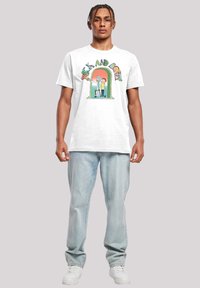 Hvit bomulls t-skjorte med grafisk trykk av tegneseriefigurer og tekst. Kombinert med lyseblå denim jeans og hvite sneakers.