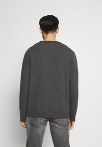 Grau gestrickter Pullover mit langen Ärmeln, rundem Halsausschnitt und geripptem Saum. Weiche Textur, einfarbig und lockere Passform. Keine ausgeprägten Muster oder Akzente.