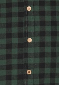 Zeleno-černá károvaná flanelová košile s dřevěnými knoflíky a jemnými detaily šití podél lég a límce.