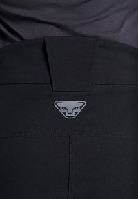 Sorte sportsbukser med en glat tekstur, en sænket talje og et gråt logo i form af en puma på bagsiden.
