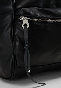 Bolso de cuero negro con un prominente cierre de plata y un diseño elegante. Incluye una pestaña texturizada para un detalle adicional.