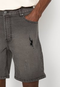 Hallid denim lühikesed püksid, millel on kulunud disain, frayed alad ja taskud. Kangas on pehme tekstuuriga ja standardse lõikega.