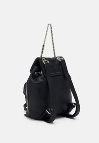 Sac à dos en cuir noir avec texture matelassée. Doté d'une bandoulière en chaîne, de poches latérales et d'accents en métal argenté. Forme structurée.