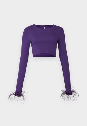 Top roxo cropped de manga longa feito de tecido canelado, com detalhes transparentes e desfiados nas mangas para adicionar textura.