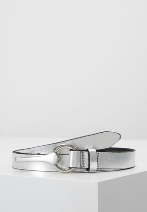 Zilverkleurige metalen leren riem met een ronde zilveren gesp en puntig uiteinde, opgerold weergegeven op een witte ondergrond.